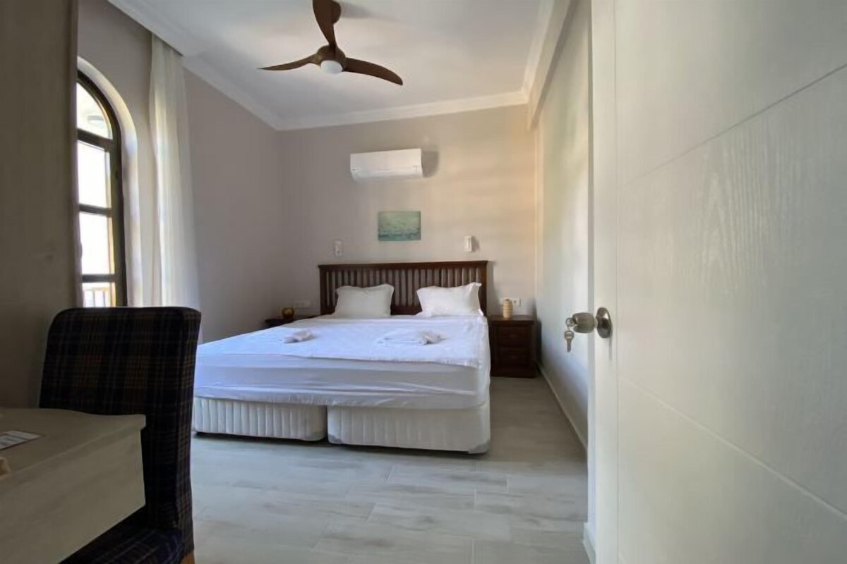 A bedroom with a bed, a ceiling fan, a window, and a door.
