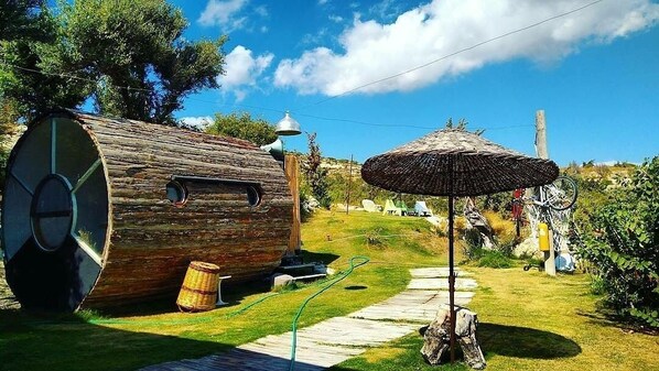A rustic outdoor setting with a wooden barrel structure, a thatched umbrella, and a bicycle. - Vadi Alacati (Cesme)