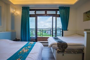 Een hotelkamer met twee bedden, een groot raam met gordijnen, uitzicht op een brug en een kroonluchter.
