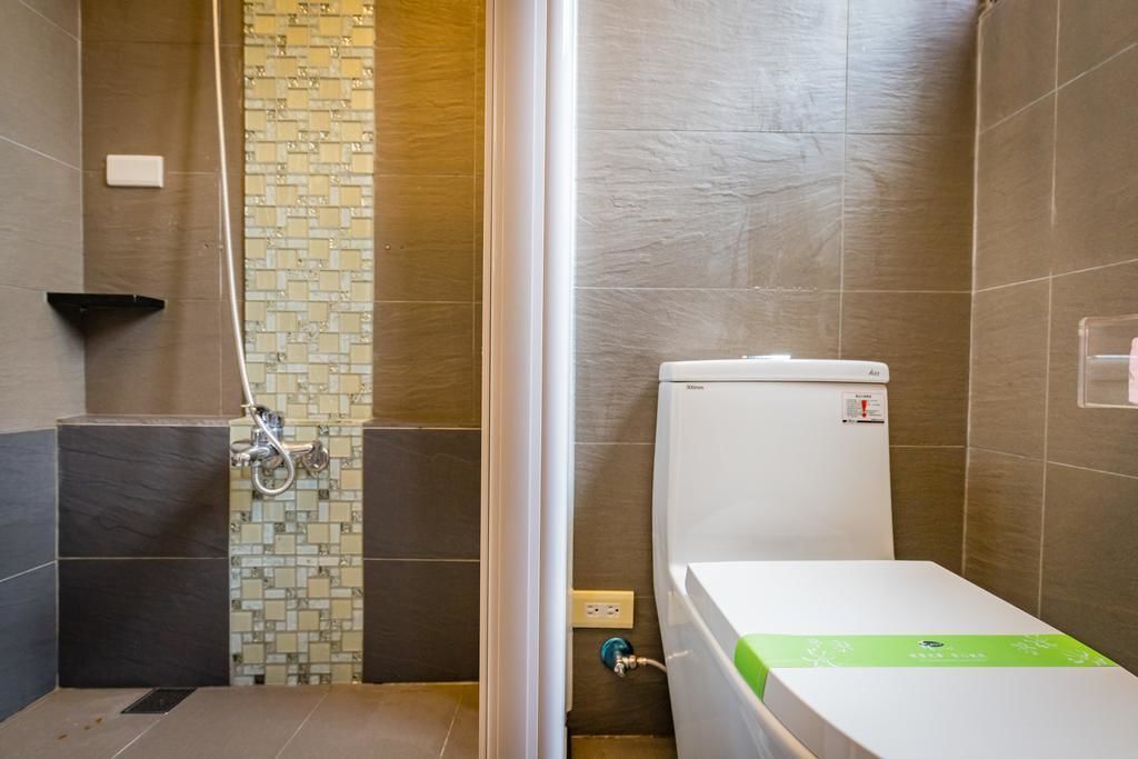 A bathroom with a shower, toilet, and a tiled wall with a mosaic pattern.