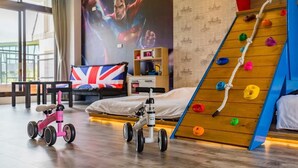 A bedroom with a bed, a climbing wall, a tricycle, and a large superhero mural. - Yanduo Homestay (Luodong)