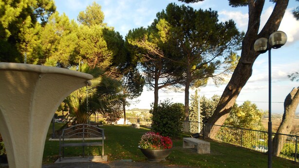 A stone pathway leading to a fountain, surrounded by trees and a bench. - B&B Severini (Morrovalle)