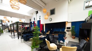 A spacious lobby with a modern design, featuring a mix of seating areas, a staircase, and a large screen. - Hotell Kvarntorget (Uppsala)