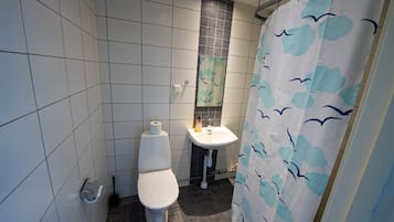 Un baño con inodoro, lavabo y cortina de ducha.