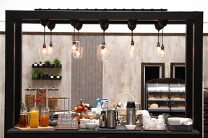 A breakfast buffet setup with various food items, beverages, and a coffee station.