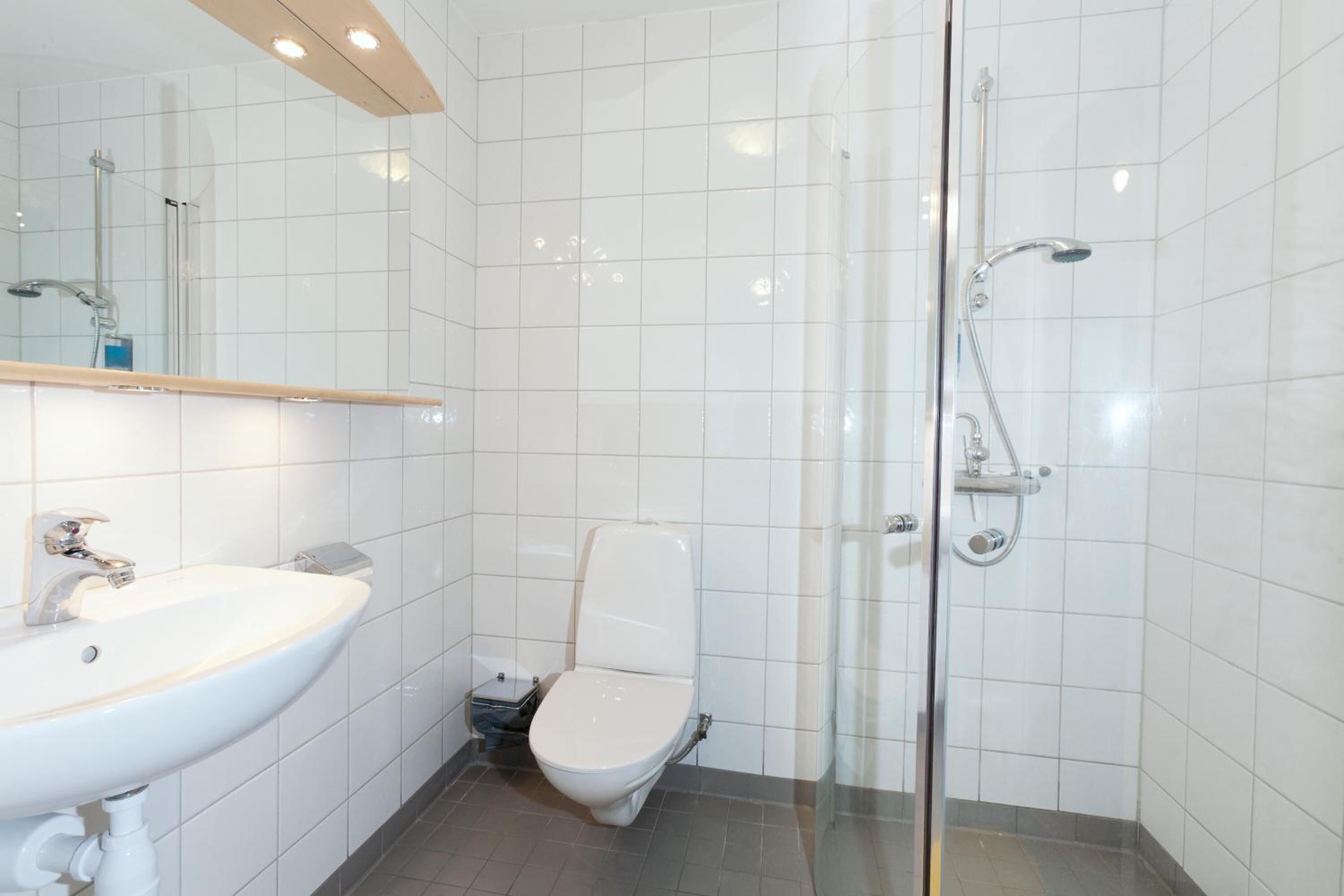 Une salle de bain moderne avec un lavabo blanc, des toilettes et une douche à parois de verre.