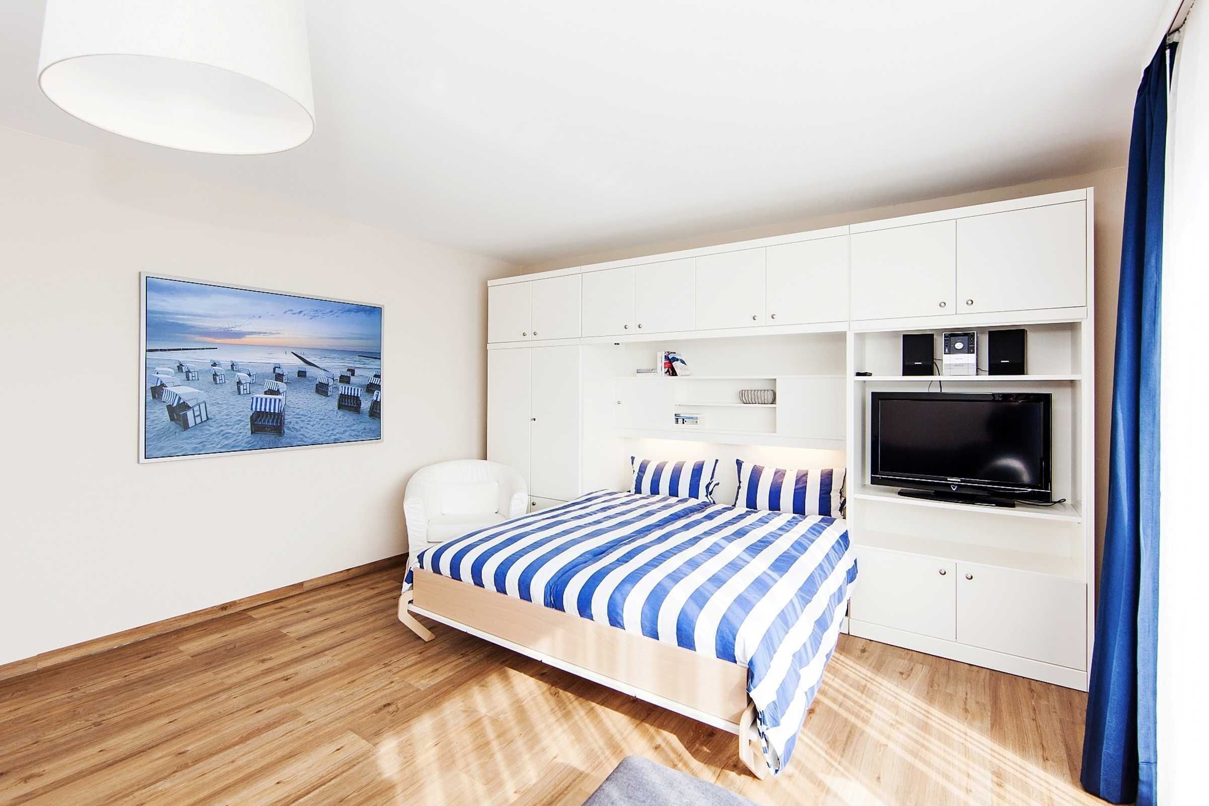 Un dormitorio con una cama, un televisor y un cuadro en la pared.