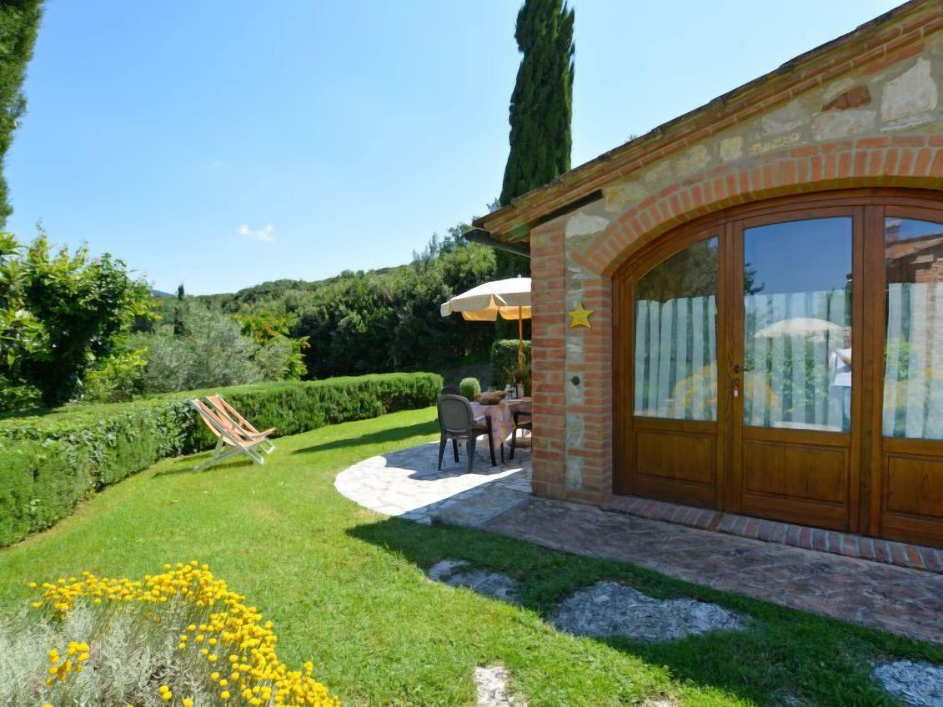 A patio area with a stone wall, a wooden door, and a table with chairs.