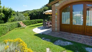 A patio area with a stone wall, a wooden door, and a table with chairs. - San Lorenzo by Interhome (Gambassi Terme)
