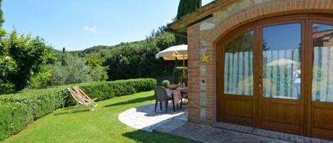 A patio area with a stone wall, a wooden door, and a table with chairs.