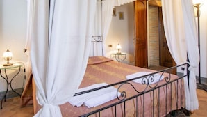 A four-poster bed with white curtains, a wooden door, and two bedside tables with lamps. - San Lorenzo by Interhome (Gambassi Terme)