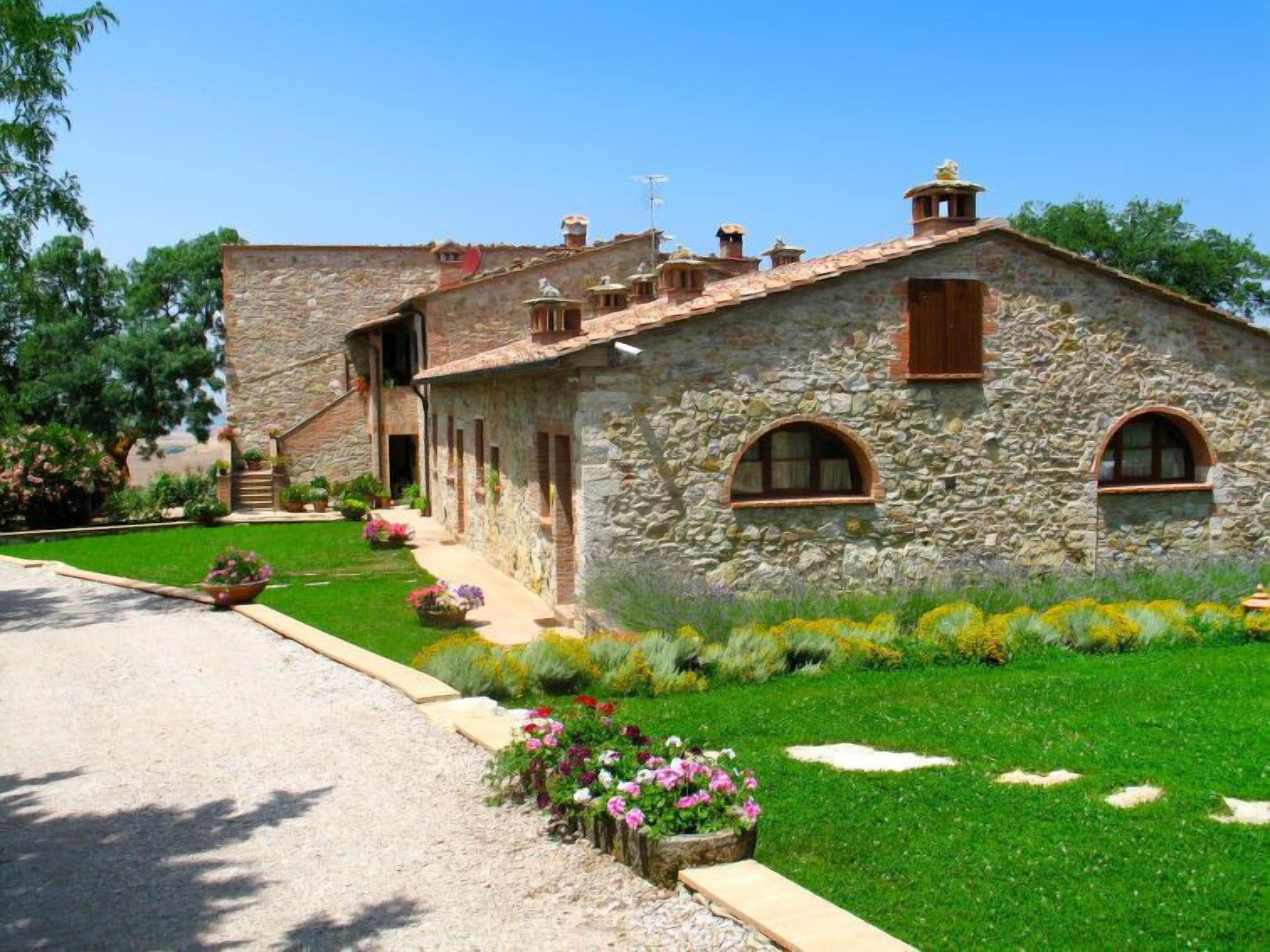 A stone building with a sloped roof, arched windows, and a small porch.