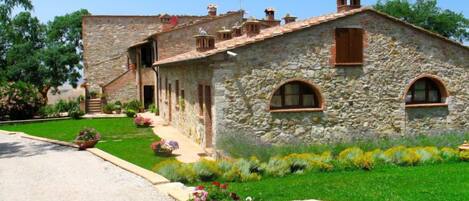 A stone building with a sloped roof, arched windows, and a small porch.