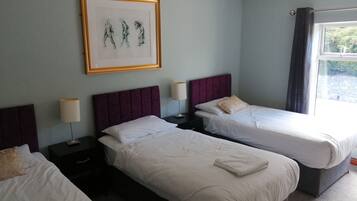 A hotel room with two beds, a framed artwork on the wall, and a window with curtains.