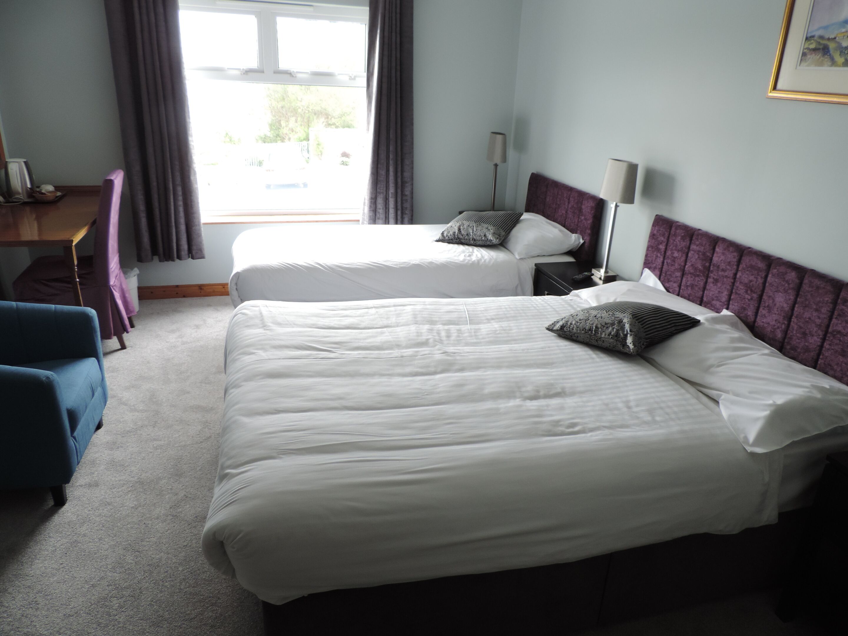 Een hotelkamer met twee bedden, een bureau en een stoel.