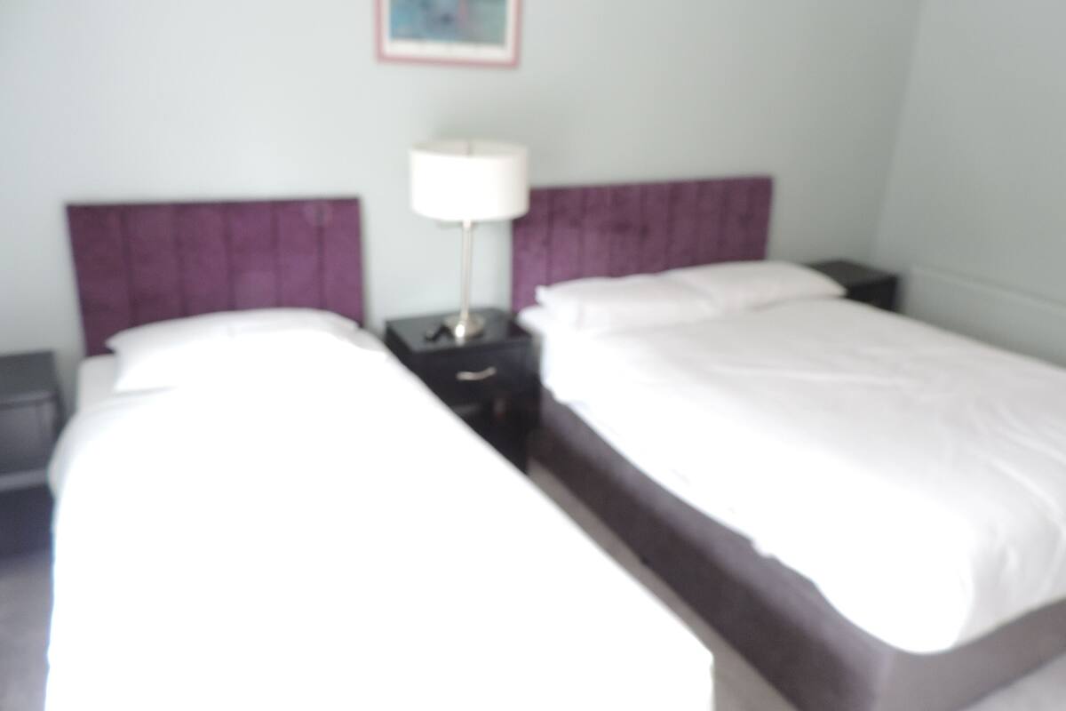 Une chambre d’hôtel avec deux lits, une table de chevet et une lampe.