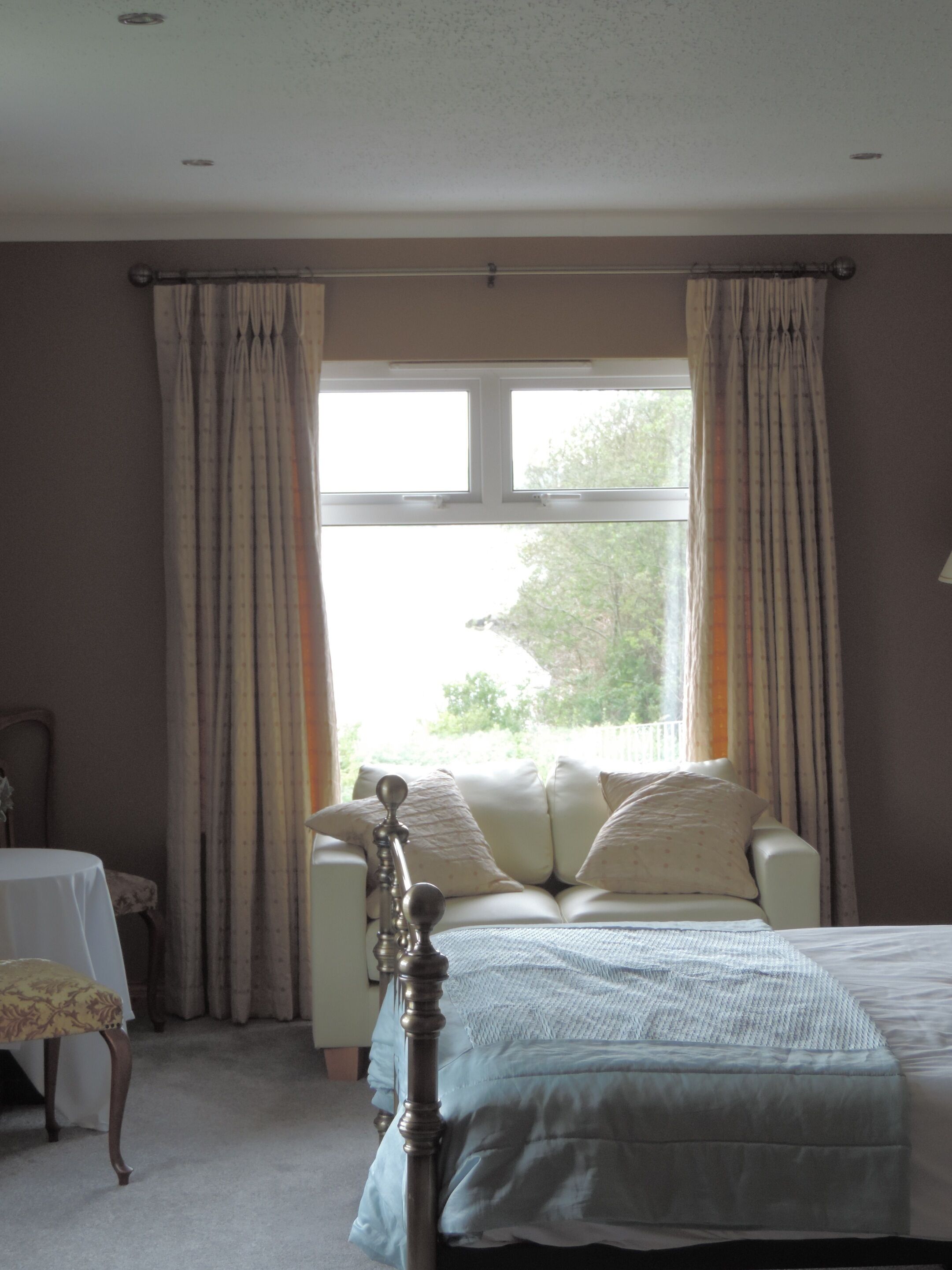 A bedroom with a bed, a nightstand, and a window with curtains.