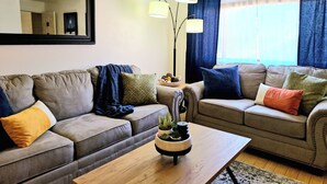 A living room with two sofas, a coffee table with a plant, and a mirror on the wall. - NEWLY UPGRADED Beautiful One Bedroom, One Bath, Sports Village Condo (St. George)
