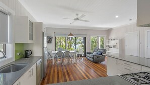 A modern kitchen with a dining area, a sofa, and a view of the outdoors. - Seascape - 154 Camden Head Rd Dunbogan (Dunbogan)