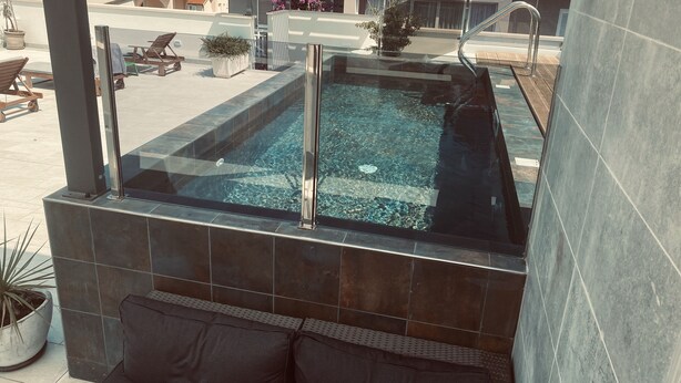 A rooftop pool with clear water, surrounded by dark tiles and a glass barrier. - Casa di Lavanda (Hvar)