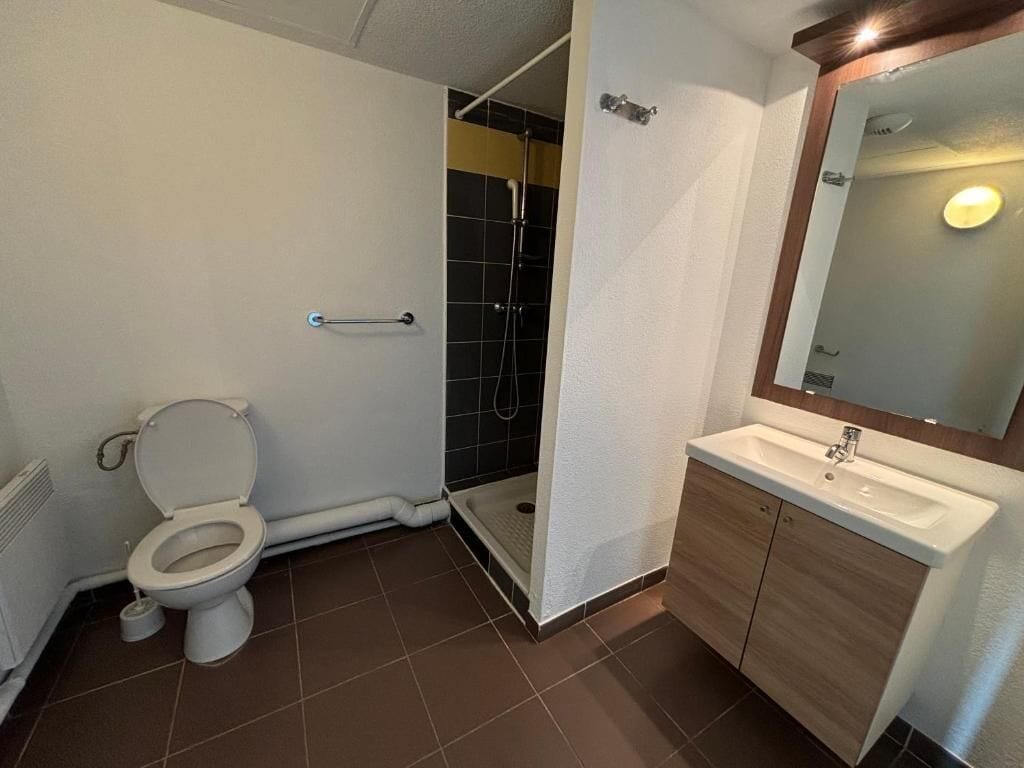 A bathroom with a toilet, shower, and sink.