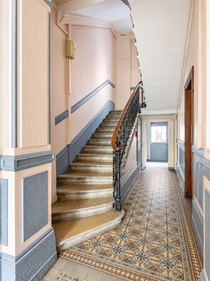 Eine prächtige Treppe mit aufwendiger Geländerarbeiten und einem gemusterten Boden, die zu einer Tür am Ende führt.