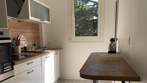Een keuken met witte kastjes, een houten aanrechtblad en een vloer met een patroon van tegels.
