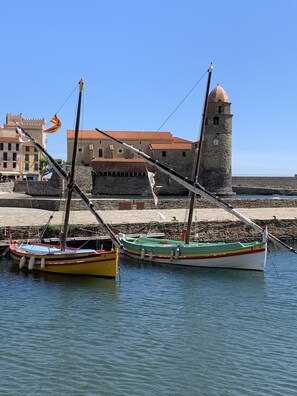 Two boats docked at a harbor with a historic building and a tower in the background.
