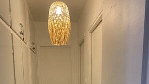 Een gang met patroon vloertegels, een deur aan het einde en een hangende lamp.