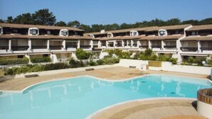 A hotel with multiple balconies, a swimming pool, and a landscaped garden area. - Apartment standing Cap Ferret center (Cap ferret)