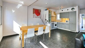 Une cuisine moderne avec des meubles de couleur grise, une table à manger en bois et des chaises blanches.