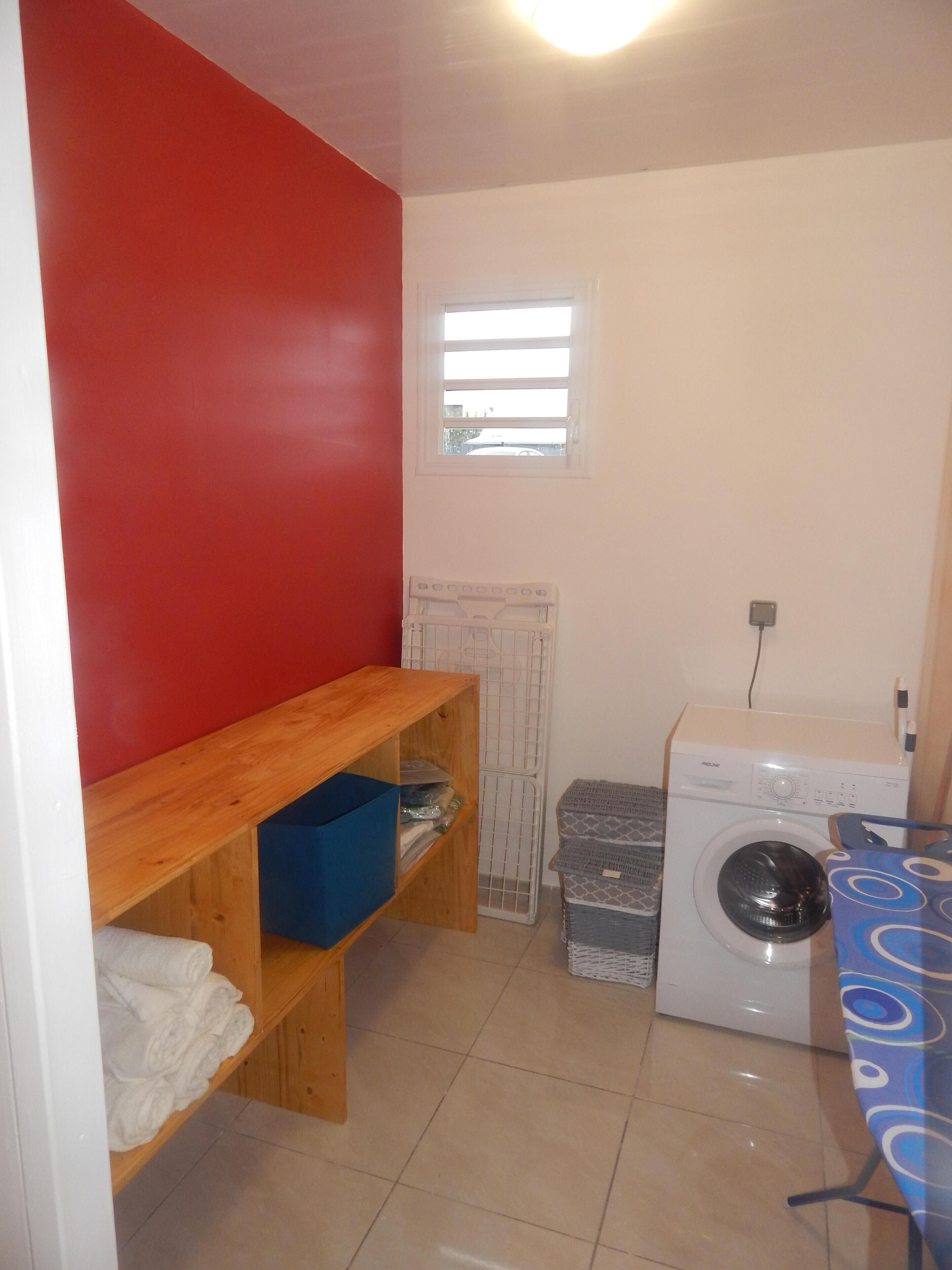 A laundry room with a washing machine, a drying rack, and a small window.