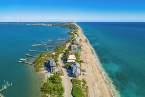 An aerial view of a coastal area with a beach, a pier, and several buildings.