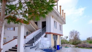 Una casa de dos pisos con una escalera que conduce al nivel superior, un área de piscina y vista al mar.