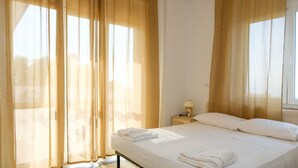 Una habitación de hotel con una cama, una mesita de noche, una lámpara y cortinas traslúcidas.
