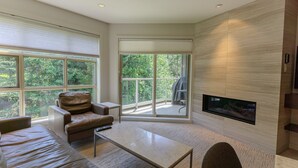 A modern living room with a leather sofa, a coffee table, and a fireplace. - Aspens #451 Renovated Ski-in Ski-out Location! Pool, Hot tubs, sleeps 4 (Whistler)