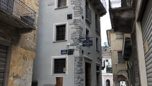 A narrow cobblestone street flanked by historic buildings with balconies and stone facades. - NicoMat Rooms (Domodossola)