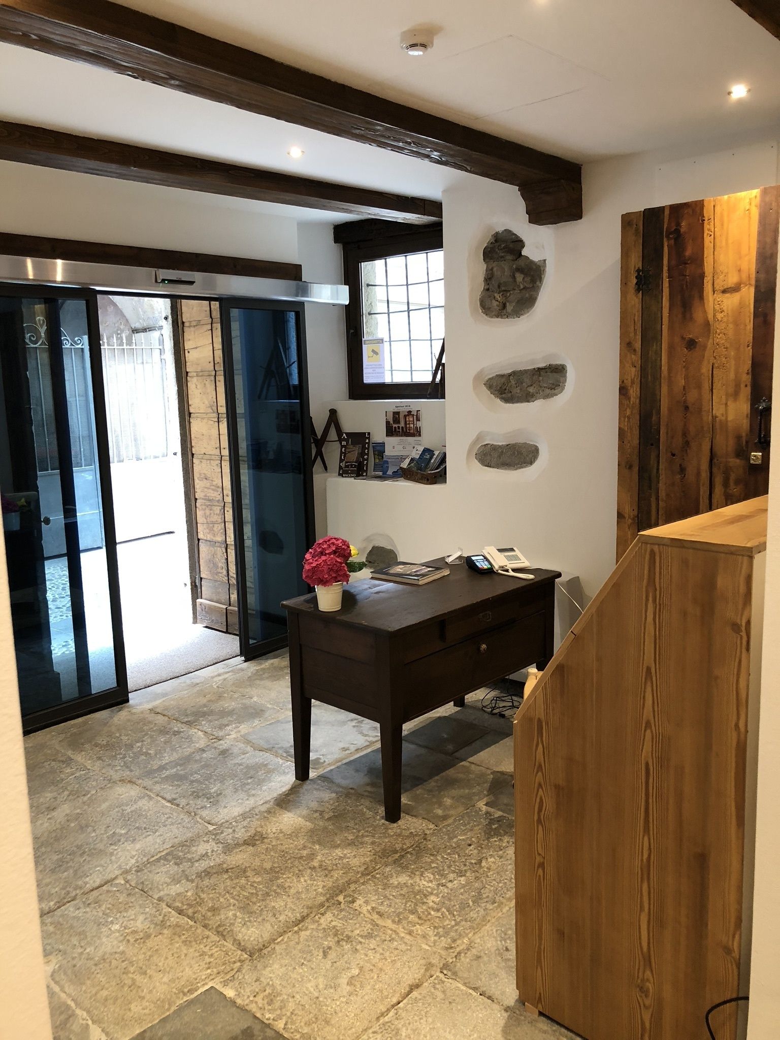 A modern interior with a dark wooden desk, stone tiles, and a stone wall with embedded rocks.