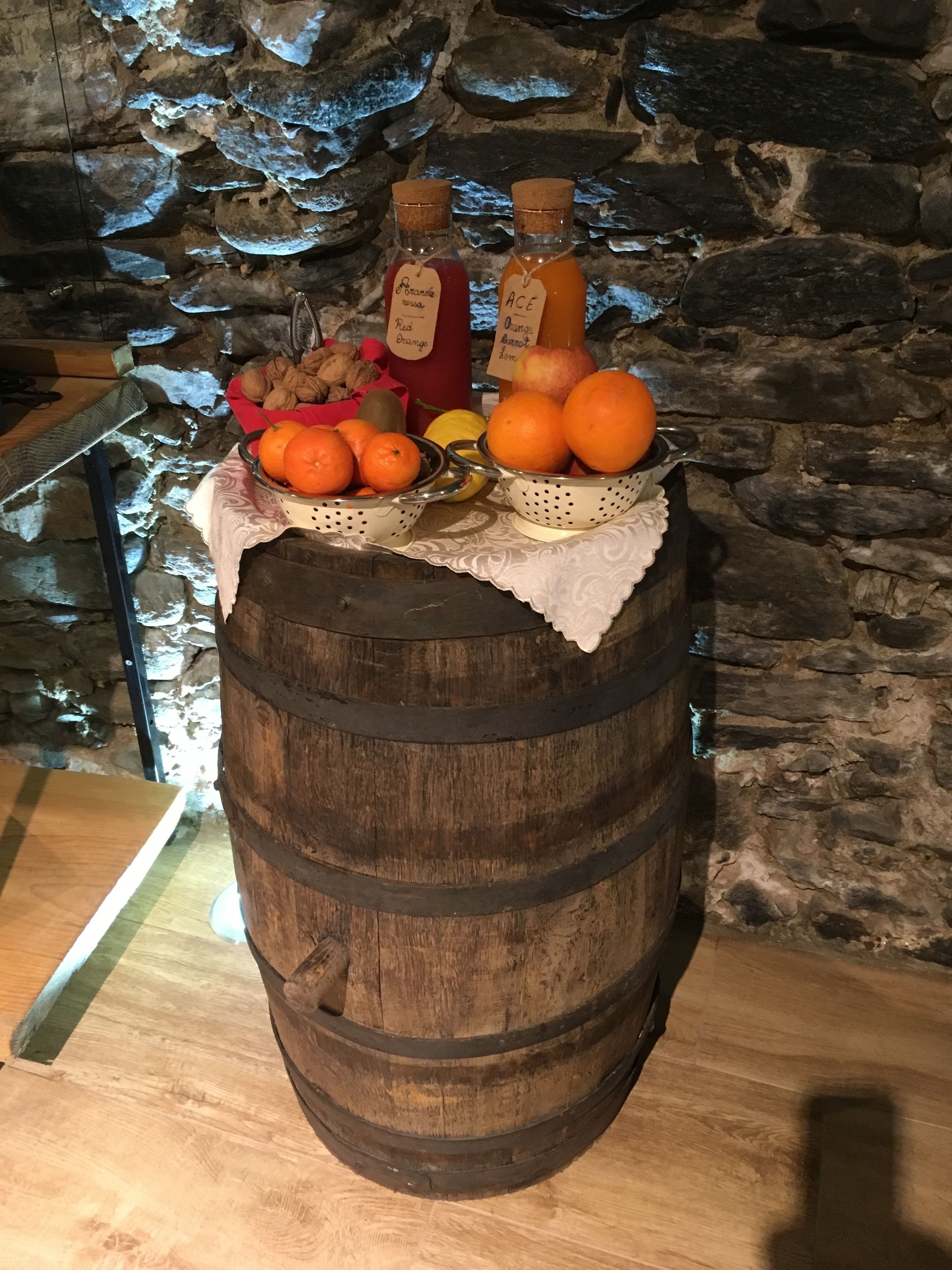 Ein Holzfass, das als Tisch dient und mit verschiedenen Früchten und Flaschen bestückt ist.
