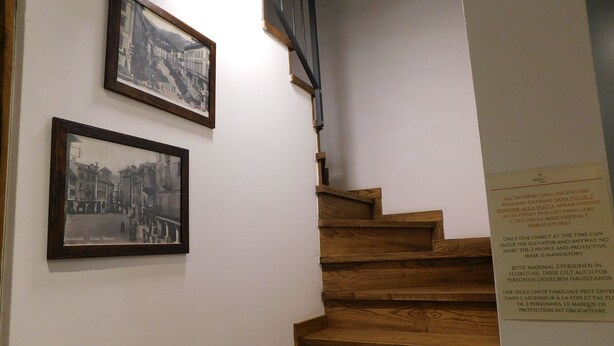 Un escalier en bois, avec deux photographies encadrées en noir et blanc accrochées au mur.