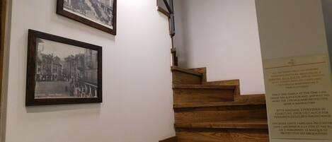 A wooden staircase with two black and white framed photographs on the wall.