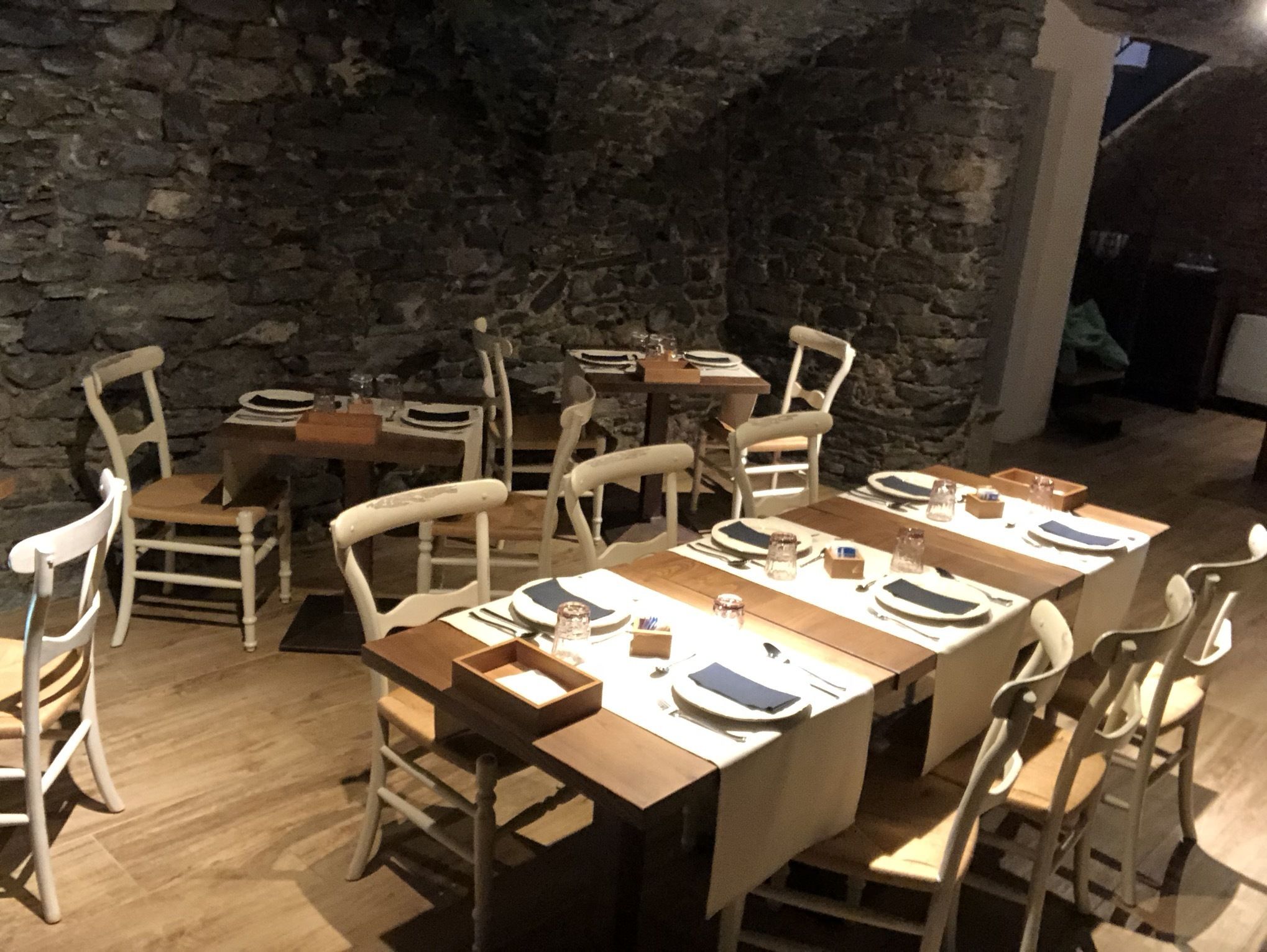 A dining area with stone walls, wooden tables, and white chairs.