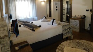 A hotel room with a large bed, a bedside table, a chair, a TV mounted on the wall, and a bathroom visible through an open door. - NicoMat Rooms (Domodossola)