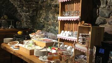 A breakfast buffet with various food items and condiments, set against a stone wall backdrop.