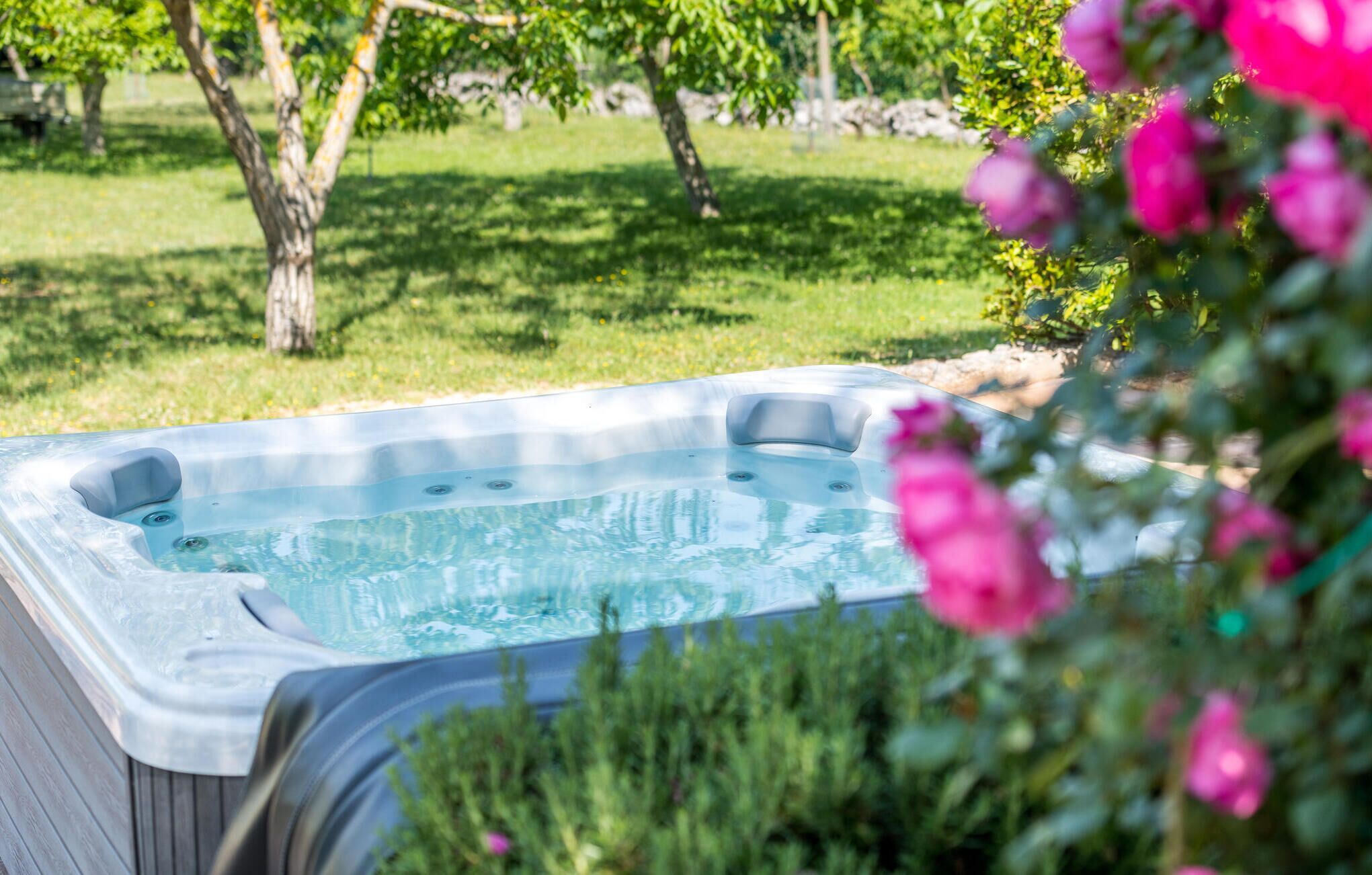 Un jacuzzi en un jardín con árboles y flores rosadas.