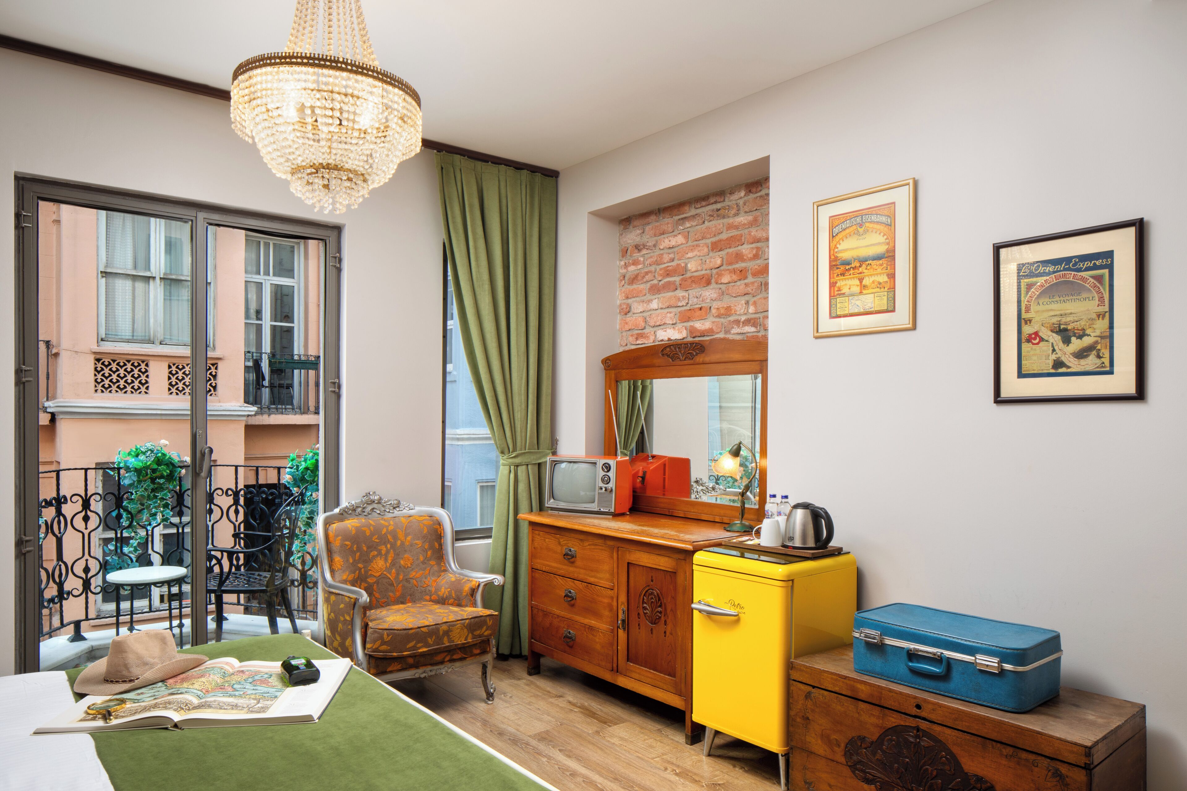 Una habitación pequeña con un aparador de madera, un mueble amarillo, una maleta azul y un televisor antiguo.