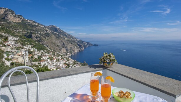 Una terraza con una mesa preparada para dos, con vista a un pueblo costero y al mar.
