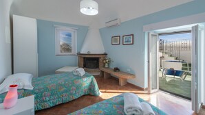 Un dormitorio con dos camas, chimenea, un banco y un balcón con vistas.