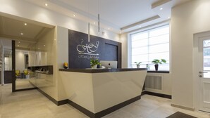 A hotel reception area with a modern design, featuring a reception desk, seating area, and large windows providing natural light. - Hotel Jakobslust (Gruenstadt)