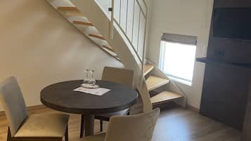 Zona pranzo con tavolo rotondo, quattro sedie e una scala che conduce a un piano superiore.